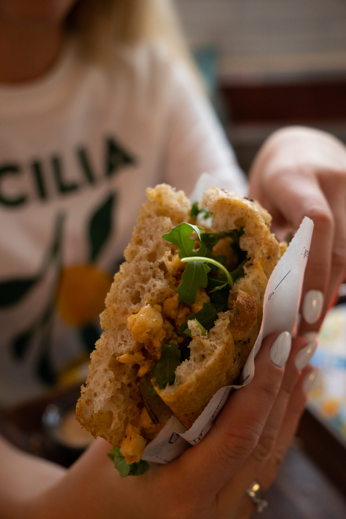 A guest holding a freshly made La Posata focaccia sandwich