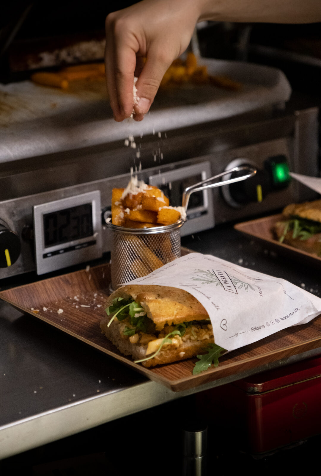 Hands finishing a focaccia sandwich in the La Posata kitchen